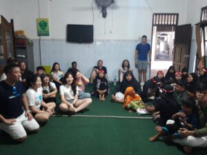 Children and volunteers sitting on the floor together.