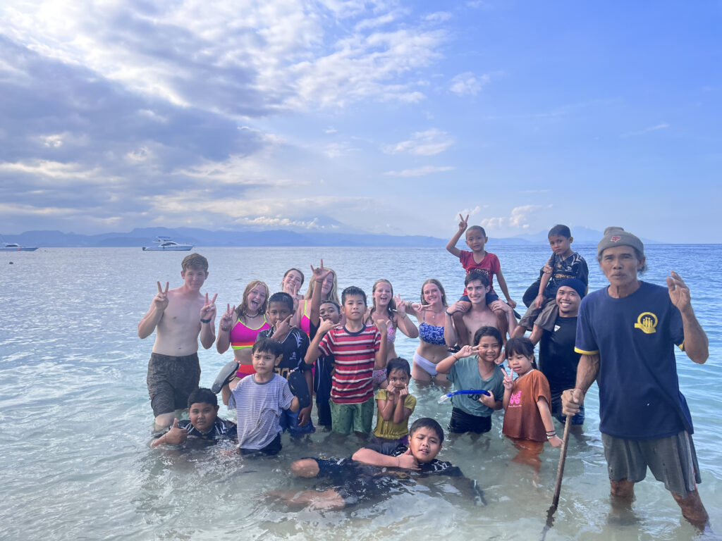 Volunteers and local community posing in the water.