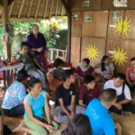 Local community members pictured sitting on the floor of the pavilion.