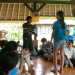 Community member and volunteer playing a game and everyone watching around them.