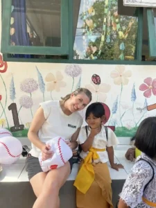 Volunteer and local child posing for a picture with baseball beach balls.
