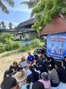 Volunteers and community members huddled together listening to a volunteer speak.