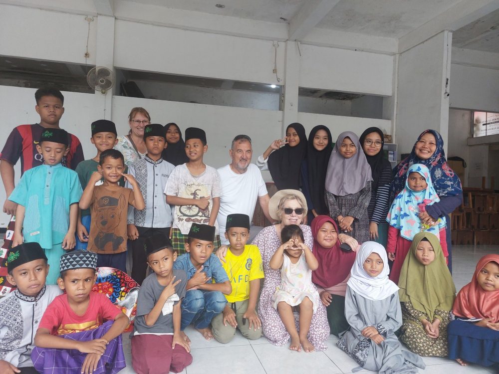 Group of volunteers and children smiling for a photo.