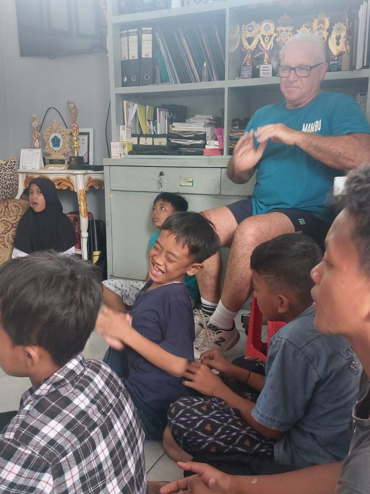a group of children of various ages sitting on the ground together.