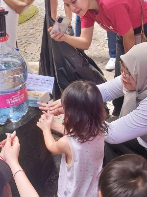 Volunteer teaching a child how to wash their hands.